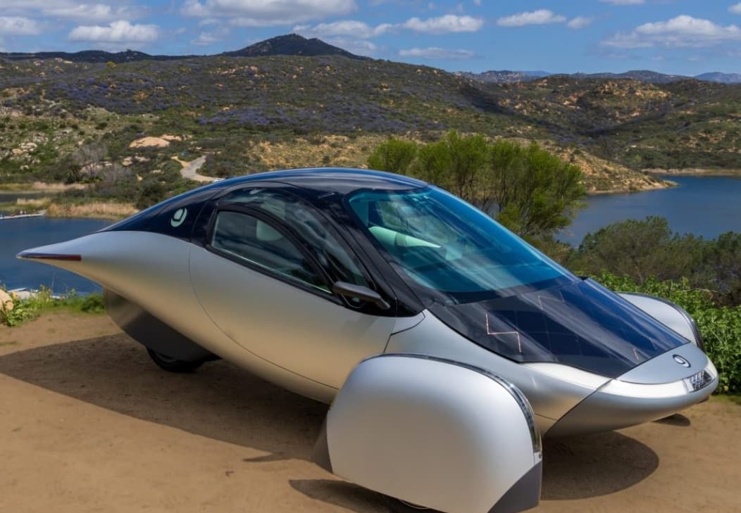 The Aptera solar electric vehicle parked above a lake